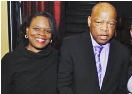 A smiling woman and a serious man posing together indoors.