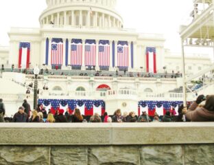 A formal event with American flags and a crowd at a government building.