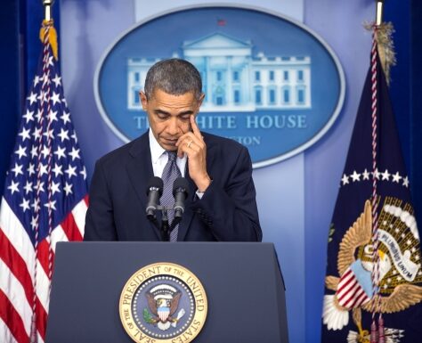 Barack Obama at a White House podium looking thoughtful.