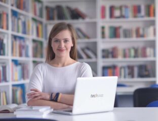 Young woman working on a laptop in a library.
