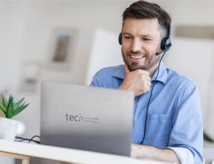 Man with headset working on laptop, smiling.