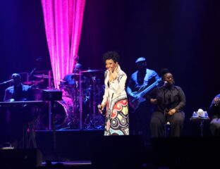 A female singer performs on stage with vibrant lighting and live band.