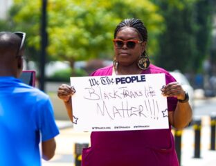 A woman holds a sign advocating for Black maternal health and dignity.