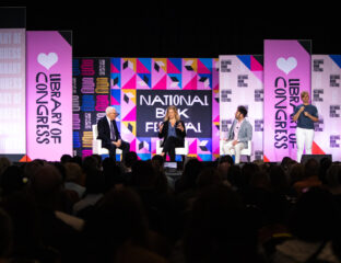 Speakers on stage at the National Festival with vibrant pink and purple banners.