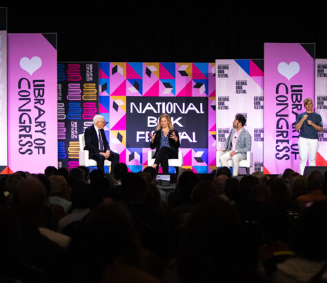 Speakers on stage at the National Festival with vibrant pink and purple banners.