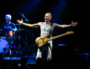 Energetic musician on stage with guitar, arms outstretched to the crowd.