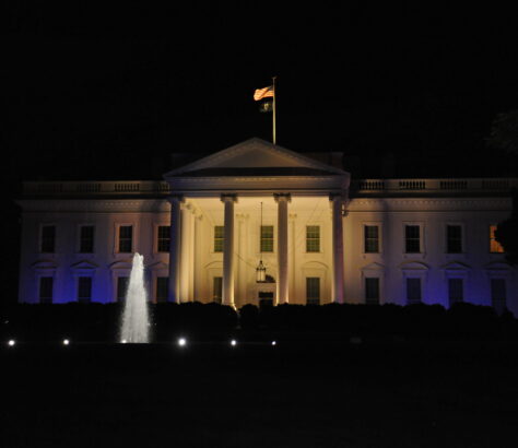 The White House illuminated at night with a fountain in front.
