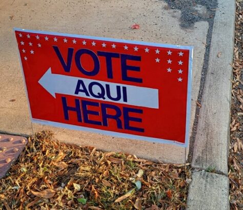 Sign directing voters to the polling place in Spanish and English.
