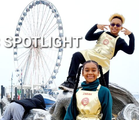 Two cheerful performers in front of a large Ferris wheel.