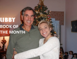 A joyful father and daughter embrace near a decorated Christmas tree.