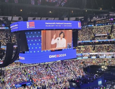 Speaker addressing a large crowd at DNC 2024 event.