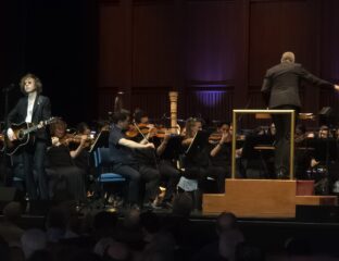 Orchestra performing live with conductor on stage.