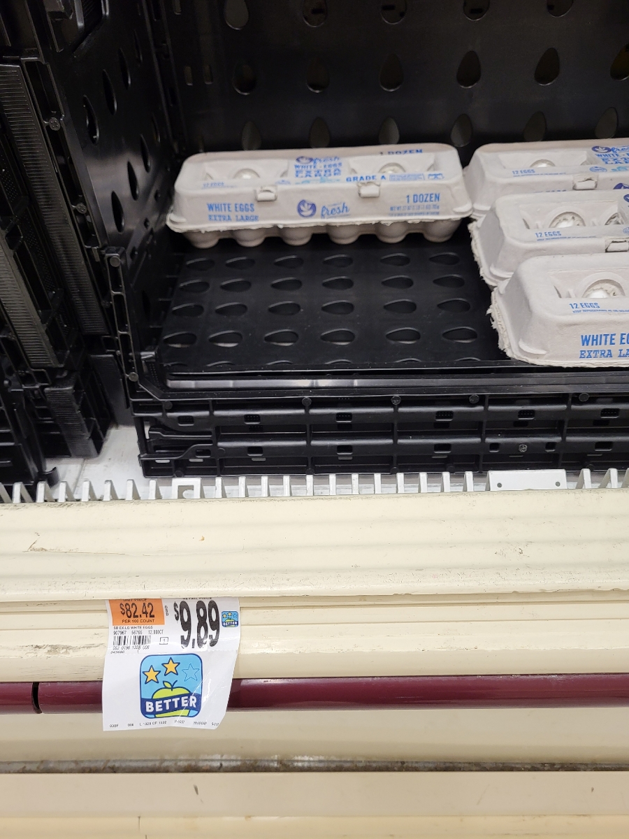 Empty egg carton shelf with only a few egg cartons left.