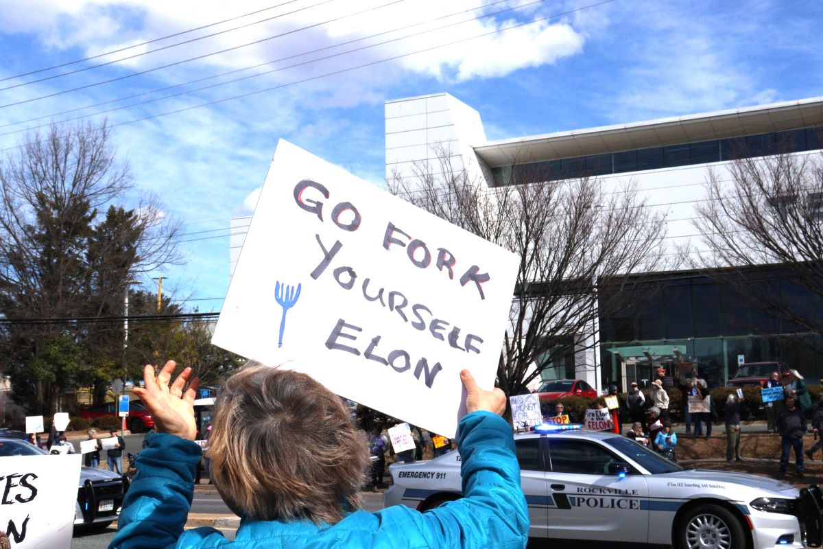 Person holding a sign that says 'Go Fork Yourself Elon' at a protest.